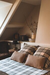 Inviting attic bedroom with boho style decor and plaid bedding in Andorra.