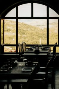 Elegant indoor dining with scenic mountain view through arched windows.