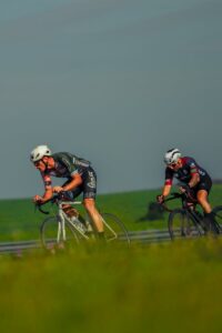 Two male cyclists racing on a sunny day, showcasing endurance and athleticism in an outdoor setting.