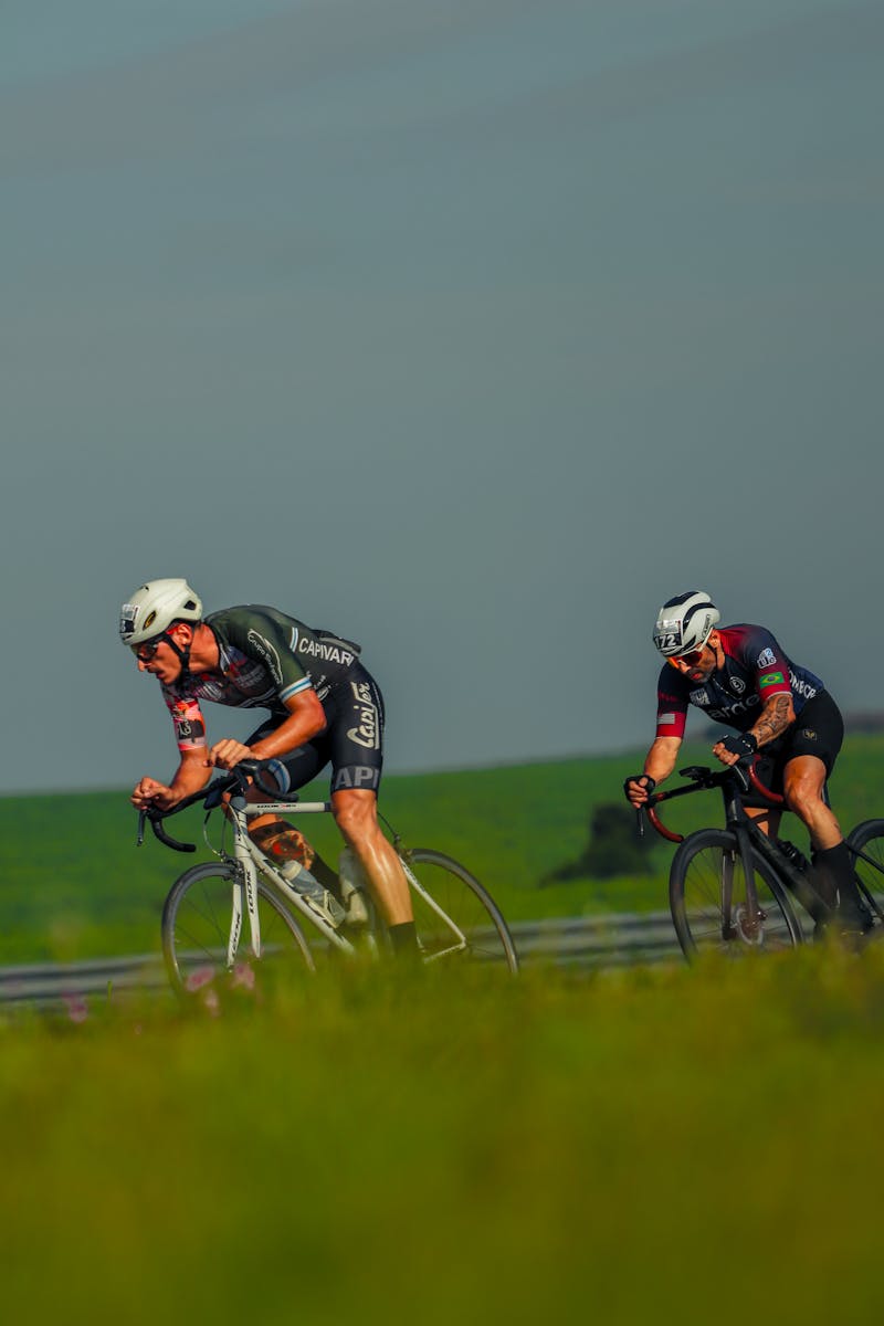 Two male cyclists racing on a sunny day, showcasing endurance and athleticism in an outdoor setting.